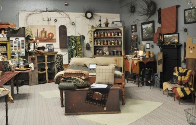 A local artisan displays homemade quilts, candles and other bedding in a display made to look like a bedroom.