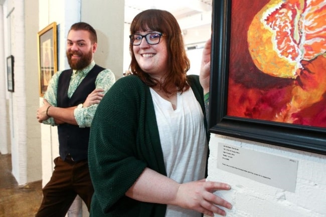 Michael Heagerty and a woman named Sarah Seib pose next to an art gallery piece inside Wildflowers Armory.