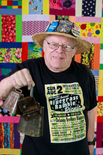 Bluegrass broadcaster Bill Knowlton holds up his well-known cow bells for a photo